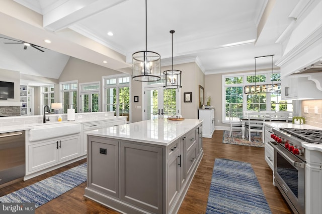 kitchen with white cabinetry, sink, stainless steel appliances, pendant lighting, and a kitchen island