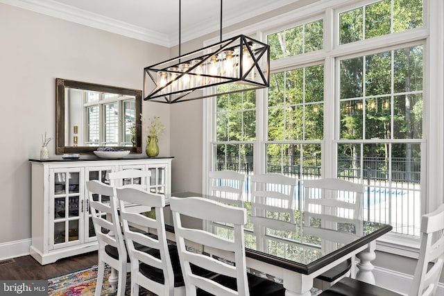 dining area with dark hardwood / wood-style flooring, an inviting chandelier, and ornamental molding