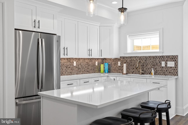 kitchen with white cabinets, stainless steel fridge, pendant lighting, and sink