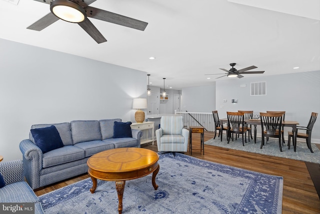 living room featuring ceiling fan and dark wood-type flooring