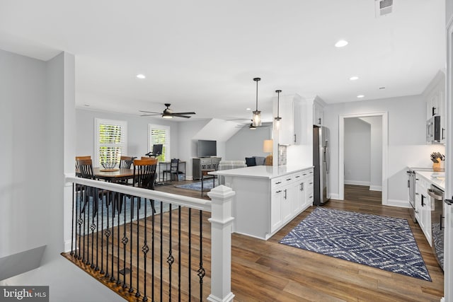 kitchen with white cabinetry, ceiling fan, stainless steel appliances, kitchen peninsula, and a breakfast bar area