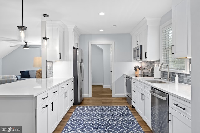 kitchen featuring appliances with stainless steel finishes, plenty of natural light, sink, white cabinetry, and hanging light fixtures