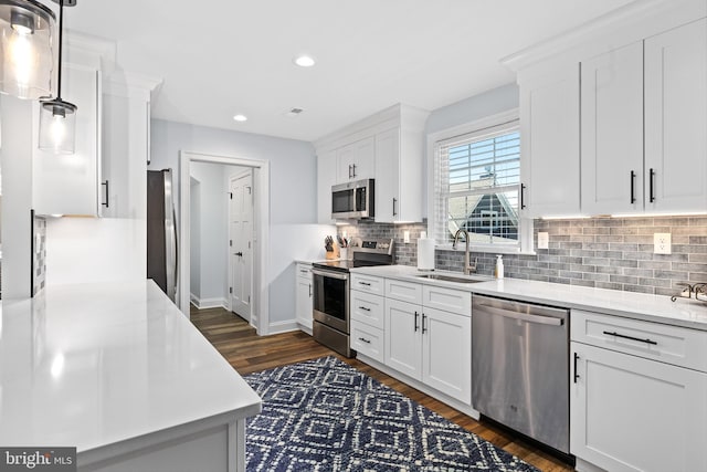 kitchen with pendant lighting, white cabinetry, sink, and stainless steel appliances