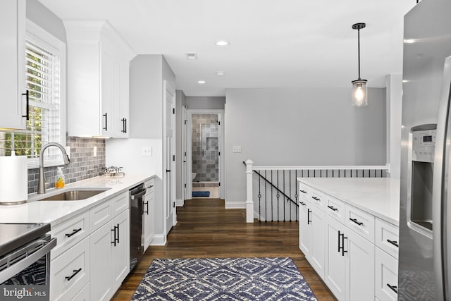 kitchen with pendant lighting, dishwasher, sink, stainless steel fridge, and white cabinetry