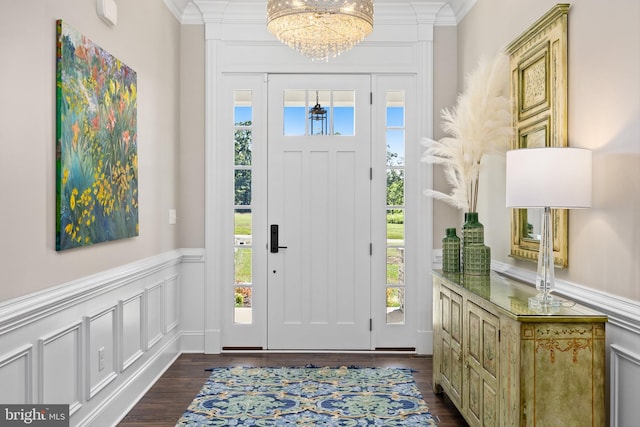 foyer with ornamental molding, dark wood-type flooring, and a notable chandelier