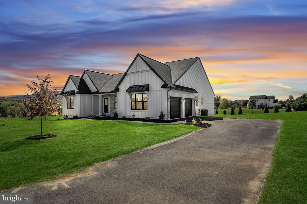 modern inspired farmhouse with a garage, central AC unit, and a lawn