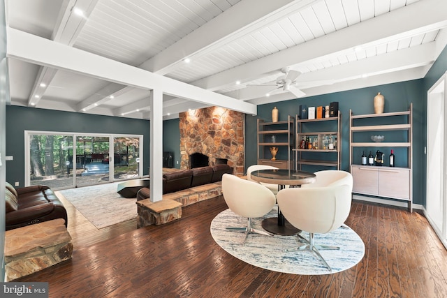 living room with ceiling fan, dark hardwood / wood-style flooring, a fireplace, and beam ceiling