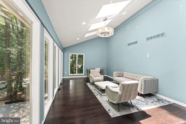 living room featuring high vaulted ceiling, dark hardwood / wood-style flooring, a skylight, and a notable chandelier