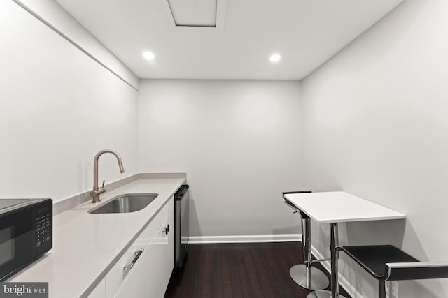 kitchen with kitchen peninsula, stainless steel dishwasher, dark wood-type flooring, sink, and white cabinetry