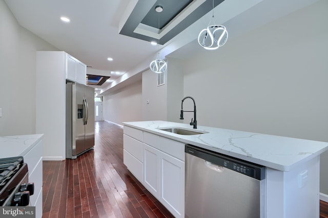 kitchen featuring a center island with sink, sink, light stone countertops, white cabinetry, and stainless steel appliances