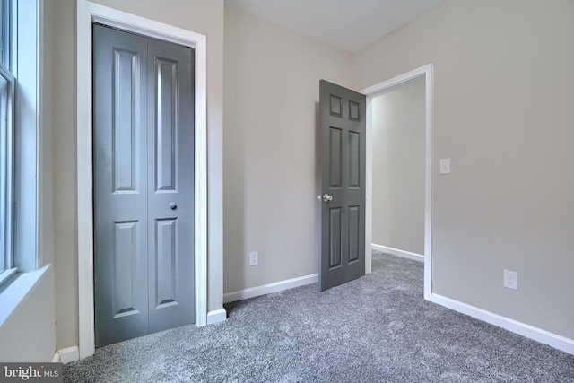 unfurnished bedroom featuring dark colored carpet and a closet