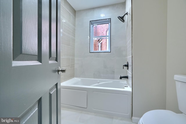 bathroom featuring tiled shower / bath combo and toilet