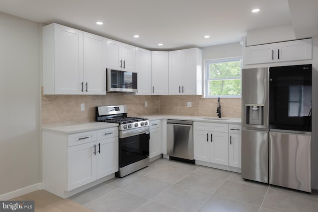 kitchen with white cabinets, appliances with stainless steel finishes, tasteful backsplash, and sink