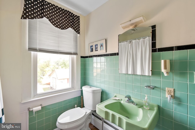 bathroom featuring toilet, tile walls, and sink