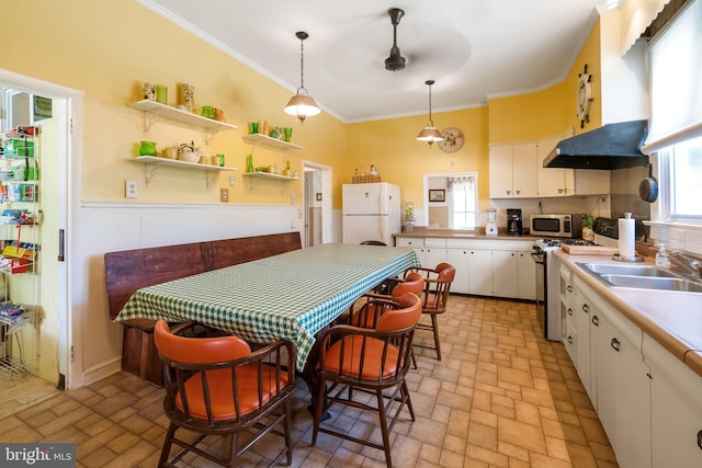 kitchen with white cabinetry, crown molding, white fridge, decorative light fixtures, and range