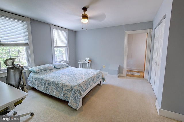 bedroom featuring ceiling fan, light colored carpet, and a closet