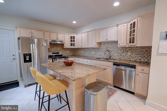 kitchen featuring sink, light stone counters, a breakfast bar, a kitchen island, and appliances with stainless steel finishes