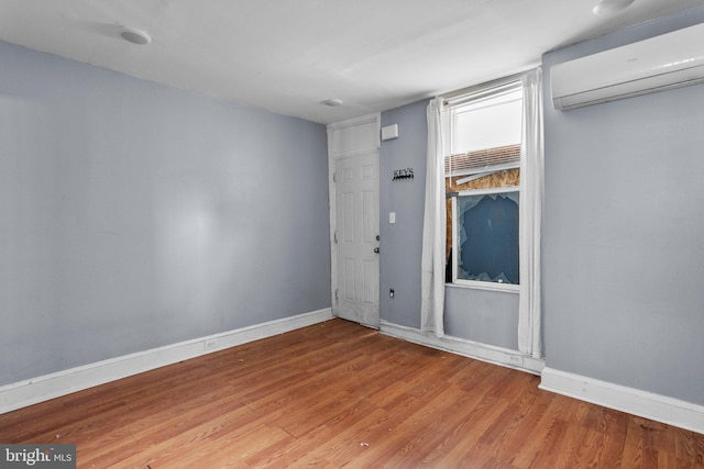 empty room with an AC wall unit and light hardwood / wood-style floors