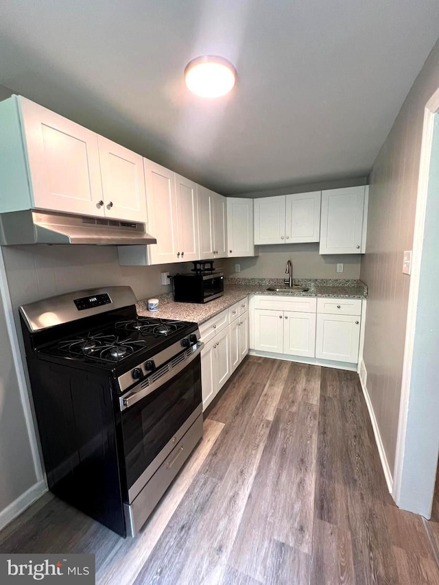 kitchen featuring sink, hardwood / wood-style flooring, light stone counters, white cabinetry, and stainless steel appliances