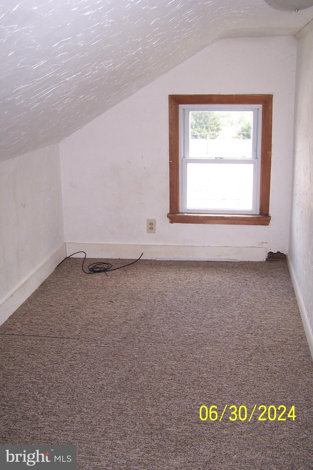 bonus room with vaulted ceiling, carpet, and a textured ceiling