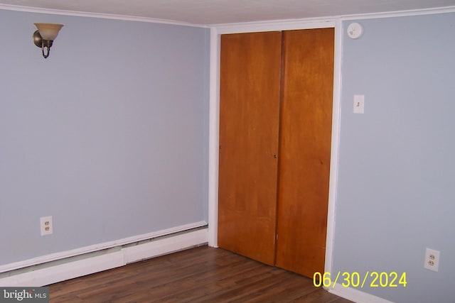 unfurnished bedroom featuring dark hardwood / wood-style flooring, a closet, baseboard heating, and crown molding