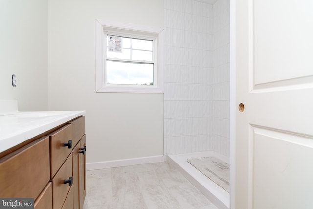 bathroom with a tile shower and vanity