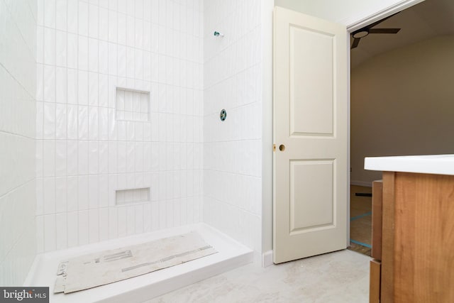 bathroom with ceiling fan and tiled shower