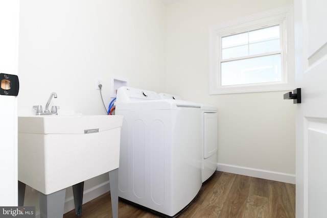 clothes washing area with washer and clothes dryer, dark wood-type flooring, and sink