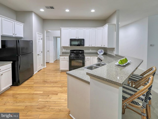 kitchen with black appliances, a kitchen bar, white cabinets, and kitchen peninsula