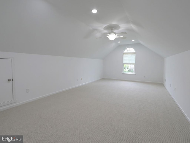 additional living space with ceiling fan, light colored carpet, and vaulted ceiling