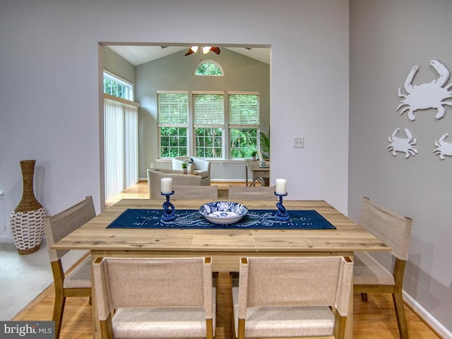 dining space with hardwood / wood-style flooring, ceiling fan, and vaulted ceiling