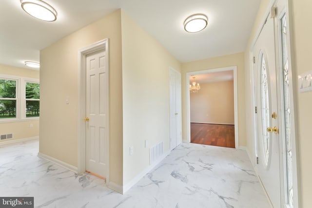 corridor with a chandelier, marble finish floor, visible vents, and baseboards