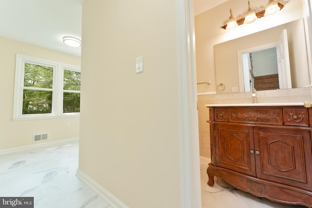 bathroom featuring visible vents, baseboards, vanity, marble finish floor, and tile walls