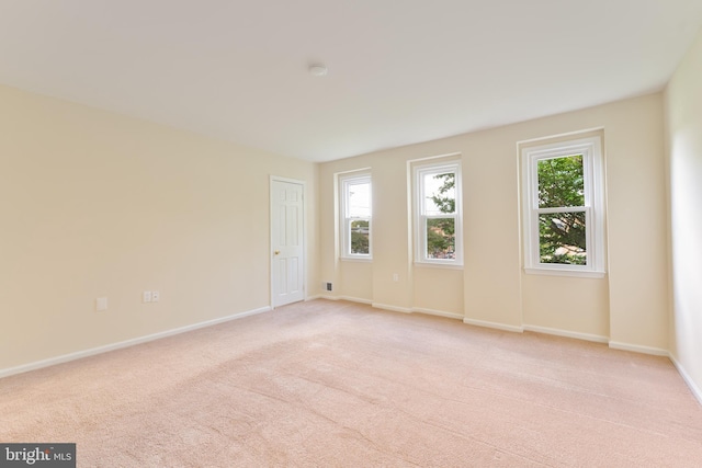 spare room featuring light carpet and baseboards