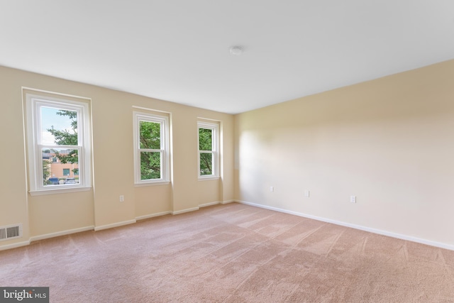 spare room with light carpet, visible vents, and baseboards