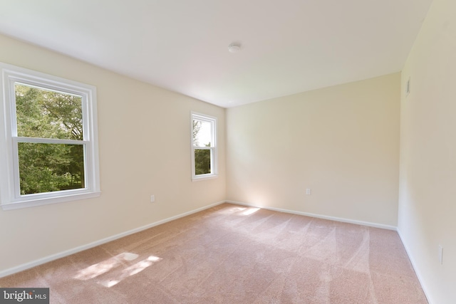 spare room featuring light carpet and baseboards