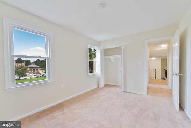 unfurnished bedroom featuring light carpet, a closet, and baseboards