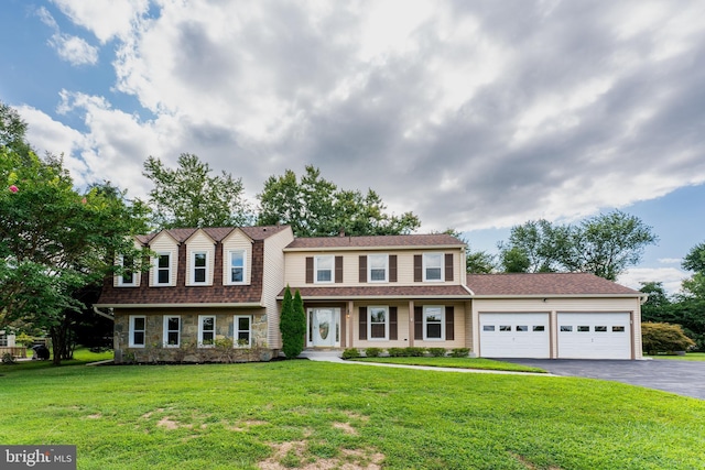 view of front of home featuring a front yard, stone siding, driveway, and an attached garage