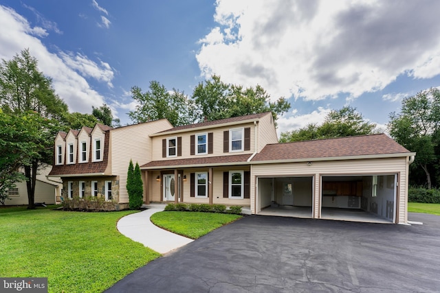 view of front of property featuring a garage, driveway, a front lawn, and roof with shingles