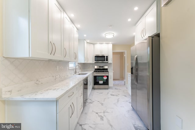 kitchen with marble finish floor, stainless steel appliances, decorative backsplash, white cabinets, and a sink