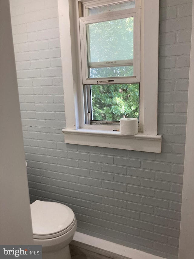 bathroom with brick wall and toilet