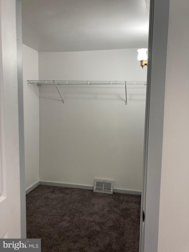 spacious closet featuring dark carpet