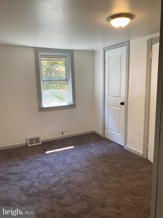 empty room featuring dark carpet