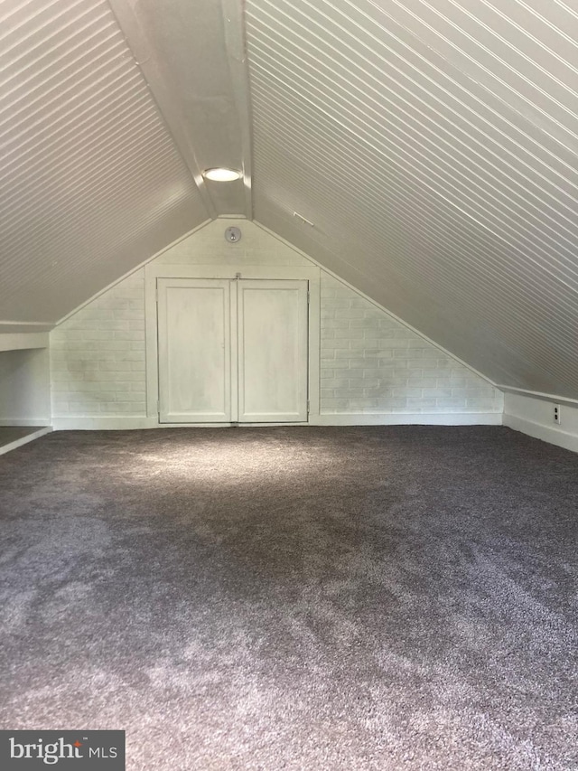 additional living space featuring dark carpet and lofted ceiling