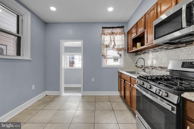 kitchen featuring light tile patterned flooring, appliances with stainless steel finishes, backsplash, and sink