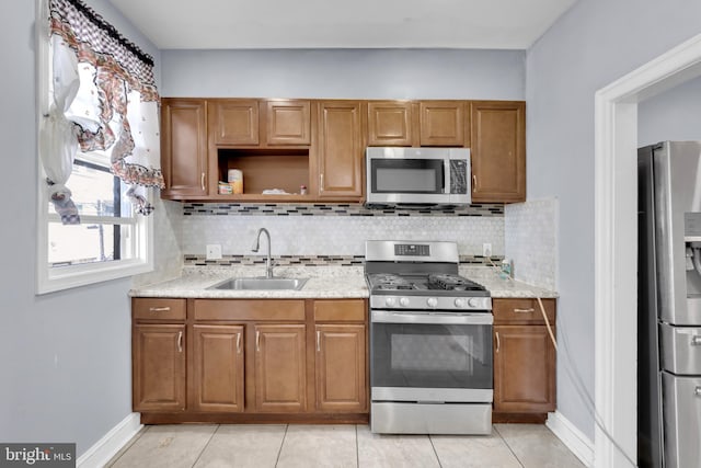 kitchen featuring decorative backsplash, sink, light tile patterned floors, and stainless steel appliances