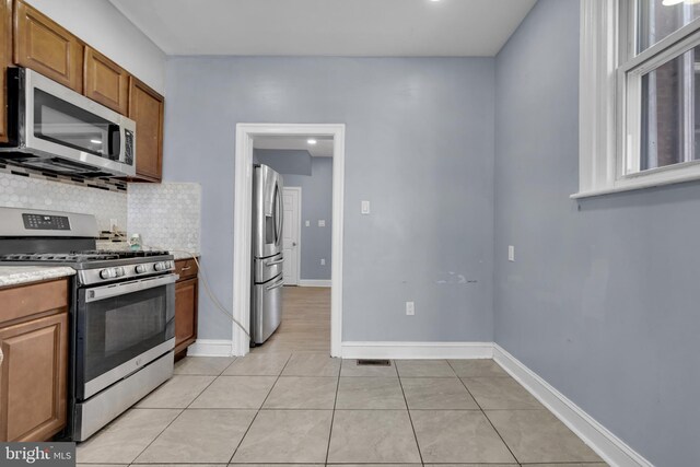 kitchen featuring decorative backsplash, light tile patterned floors, and stainless steel appliances