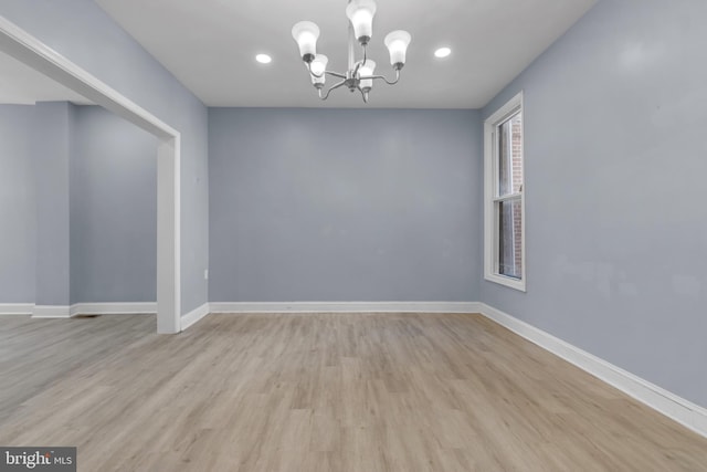 empty room with a notable chandelier and light hardwood / wood-style flooring