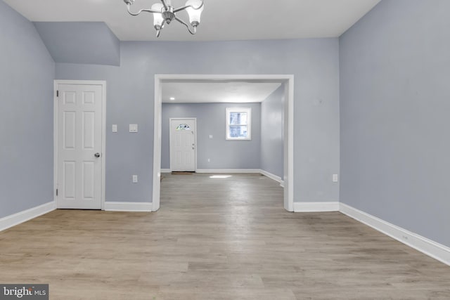 spare room featuring light hardwood / wood-style floors and an inviting chandelier