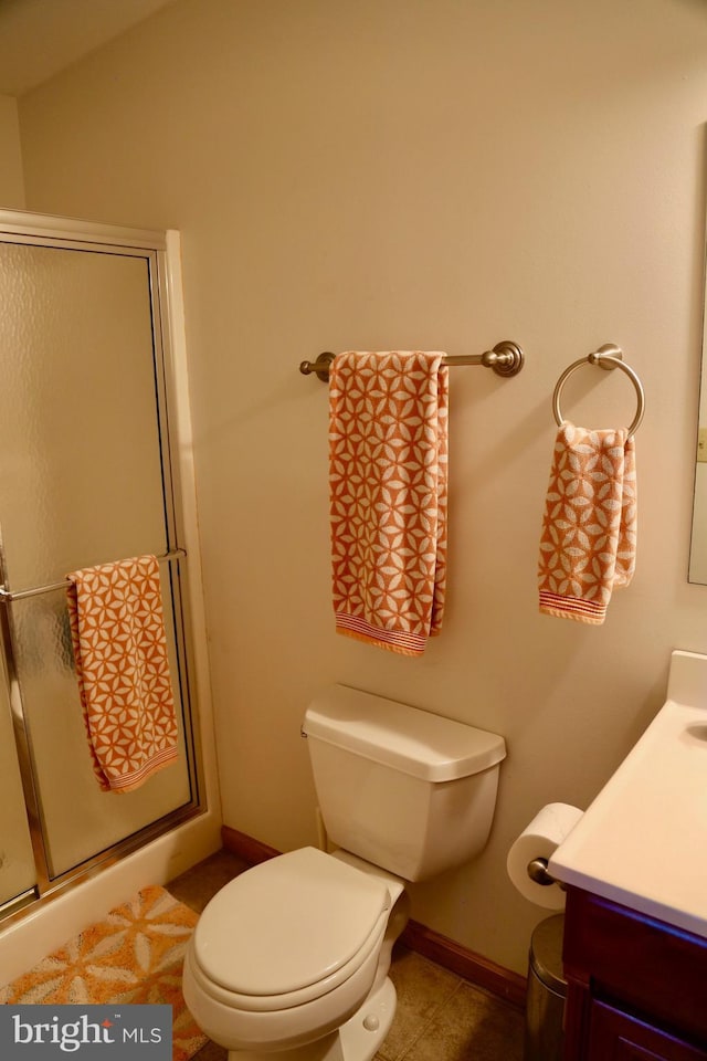 bathroom with tile patterned flooring, vanity, toilet, and walk in shower